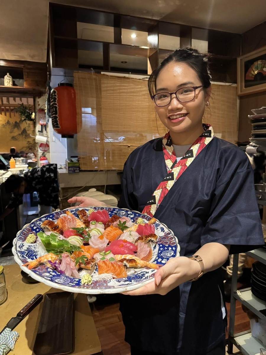 Staff member holding a large sushi and sashimi platter